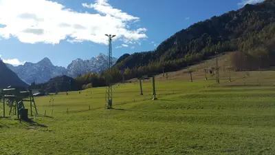 a field with a hill with a windmill in it at Hotel Alpina in Kranjska Gora