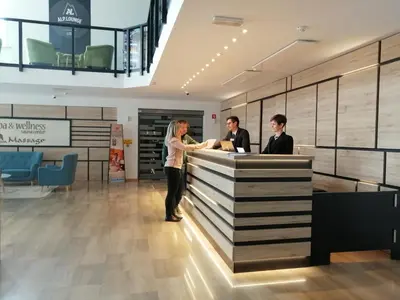 a woman standing at a counter in a lobby at Hotel Alpina in Kranjska Gora