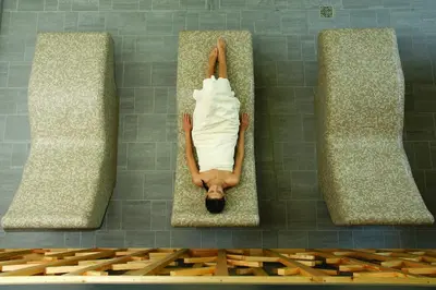 a man laying on a platform in a bath room at Hotel Špik in Kranjska Gora
