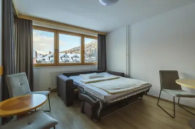 a bedroom with a bed and a table and a window at Vitranc Apartments in Kranjska Gora