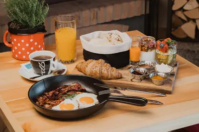 a table with a frying pan with eggs and bread at Vitranc Apartments in Kranjska Gora