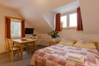 a bedroom with a bed and a table and windows at Apartments Rozle in Kranjska Gora