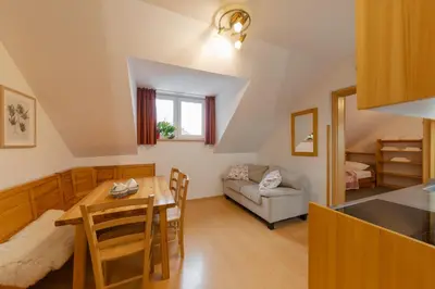 a kitchen and living room with a table and a couch at Apartments Rozle in Kranjska Gora