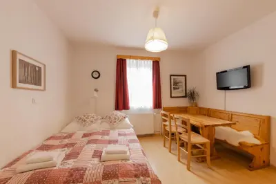 a bedroom with a bed and a table and a television at Apartments Rozle in Kranjska Gora