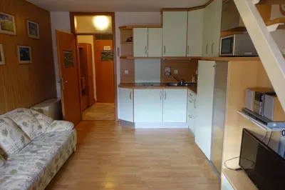 a kitchen with white cabinets and a couch in a room at Apartments Kaninska Vas in Bovec