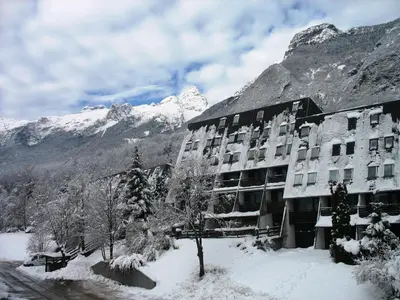 a building in the snow with a mountain at Apartments Kaninska Vas in Bovec