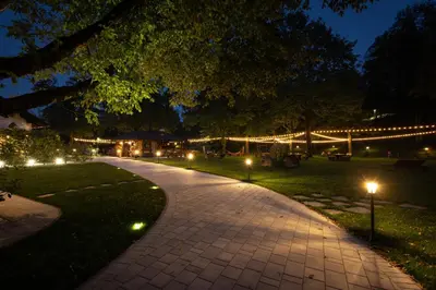 a walkway with lights in a park at night at Penzion Pibernik in Bled