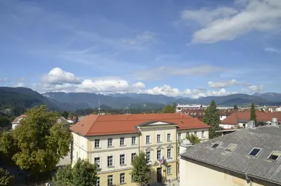 a building with a red roof with mountains in the background at Grajski Dvor in Radovljica