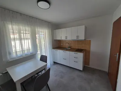 a kitchen with white cabinets and a table and chairs at Apartments Silič in Bled