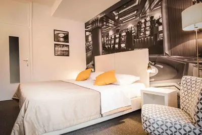 a bedroom with a bed with orange pillows and a chair at Park, Hotel & Entertainment in Nova Gorica