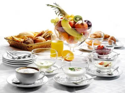 a table with cups and plates of food and a bowl of fruit at Park, Hotel & Entertainment in Nova Gorica