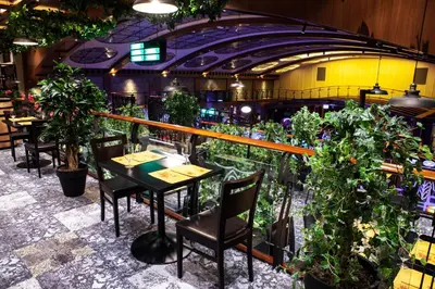 a restaurant with tables and chairs and potted plants at Park, Hotel & Entertainment in Nova Gorica