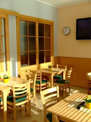 a dining room with wooden tables and chairs and a clock at Guest House Pri Gondoli in Maribor