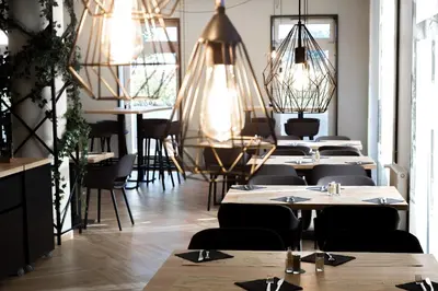 a dining room with tables and chairs and chandeliers at Lipa, Hotel & Bistro in Nova Gorica