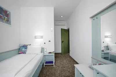 a small room with a bed and a green door at Lipa, Hotel & Bistro in Nova Gorica
