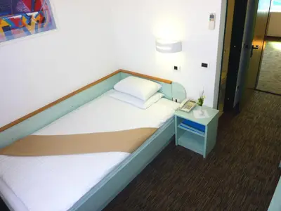 a bed in a room with a phone on a table at Lipa, Hotel & Bistro in Nova Gorica