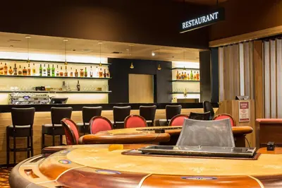 a restaurant with a bar with red chairs and tables at Korona, Resort & Entertainment in Kranjska Gora