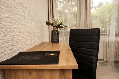 a wooden table with a black chair next to a window at Hotel Faraon in Celje