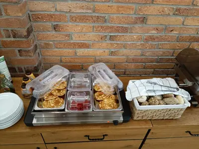 a table with trays of pastries and a brick wall at Hotel Faraon in Celje