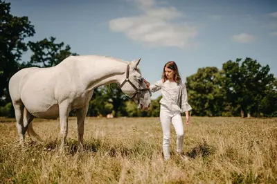 a girl standing next to a white horse in a field at Hotel Maestoso - Lipica in Sežana