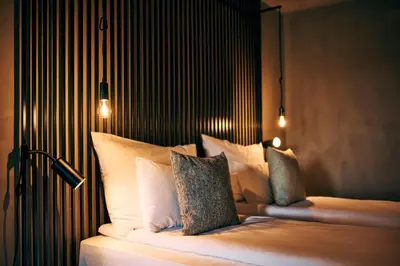 a bedroom with a bed with white pillows and lights at Hotel Maestoso - Lipica in Sežana