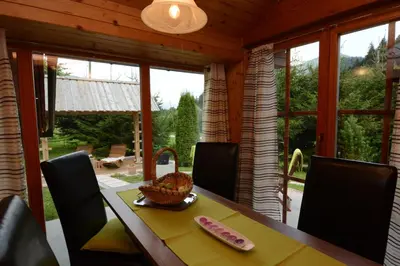 a dining room with a table and chairs and windows at Studio ALPIKA in Luče