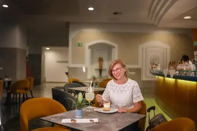 a woman sitting at a table with a glass of wine at Hotel Zdravilisce - Thermana Lasko in Laško