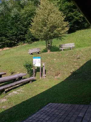 a park with benches and a sign in the grass at Brunarica in Globoko