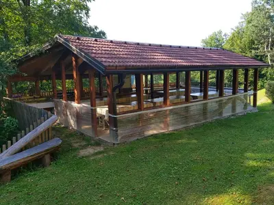 a wooden gazebo with a roof on the grass at Brunarica in Globoko
