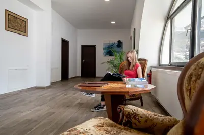 a woman sitting at a table in a room at Guesthouse Stari Mayr in Kranj