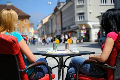 two women sitting at a table on a street at Guesthouse Stari Mayr in Kranj
