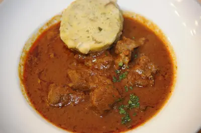 a white plate with a bowl of soup with a tortilla at Guesthouse Stari Mayr in Kranj