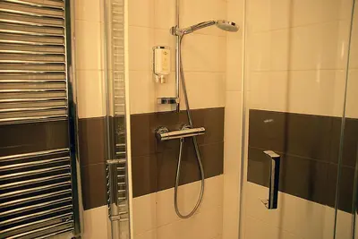 a shower in a bathroom with black and white tiles at Hotel Opara in Trebnje
