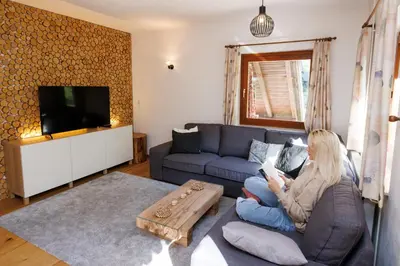a woman sitting on a couch in a living room at Chalet Ana Bohinj in Bohinj