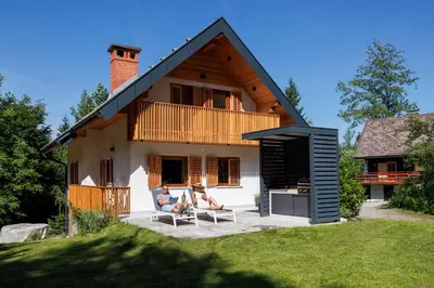 two people sitting on chairs in front of a house at Chalet Ana Bohinj in Bohinj