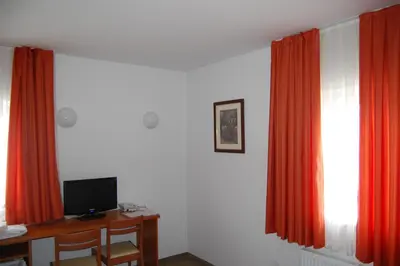 a room with red curtains and a desk with a computer at Penzion Pri Slovenc in Dol pri Ljubljani