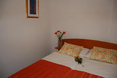 a bed with two pillows and a vase with flowers on it at Penzion Pri Slovenc in Dol pri Ljubljani