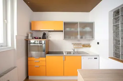 a kitchen with orange cabinets and a sink at Skyscraper Apartment Tour As Ljubljana in Ljubljana