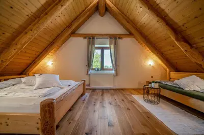 a attic bedroom with two beds and a window at Kmečka Hiška - Hiša vina Cuk in Lendava
