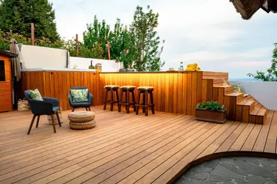 a deck with bar stools and a wooden fence at Kmečka Hiška - Hiša vina Cuk in Lendava
