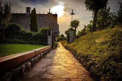 a stone path in front of a building with the sun in the background at Kmečka Hiška - Hiša vina Cuk in Lendava