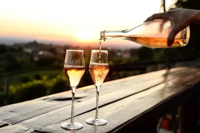 a person pouring wine into two wine glasses on a table at Hiša vina Cuk in Lendava