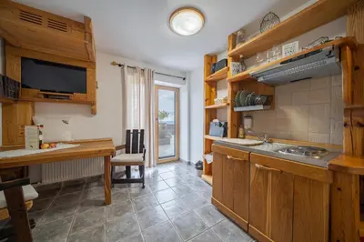 a kitchen with wooden cabinets and a table with a sink at Hiša vina Cuk in Lendava