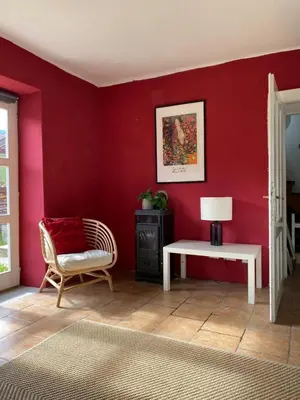 a room with a red wall with a chair and a table at Ciginj old stone house in Čiginj