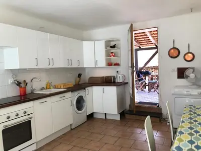 a kitchen with white cabinets and a washing machine at Ciginj old stone house in Čiginj