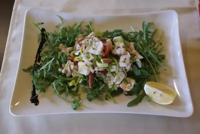 a salad on a white plate with a lemon at Hotel Prunk in Sežana
