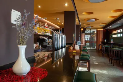 a bar with a white vase on a table with chairs at Hotel Prunk in Sežana