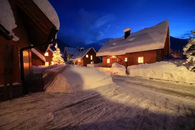 a snowy street with snow covered houses and a christmas tree at Kronau Chalet Resort in Kranjska Gora