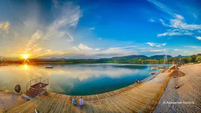a large body of water with people sitting on a dock at Hotel Razgorsek in Velenje