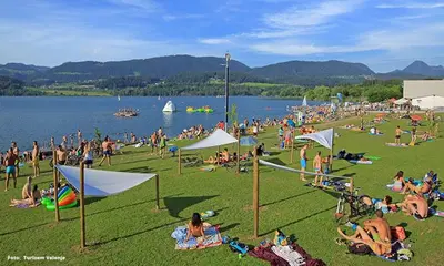 a large group of people sitting on the grass at a beach at Hotel Razgorsek in Velenje